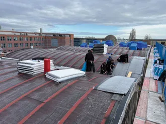 Verarbeiter verlegen eine Dachabdichtung auf einem Flachdach